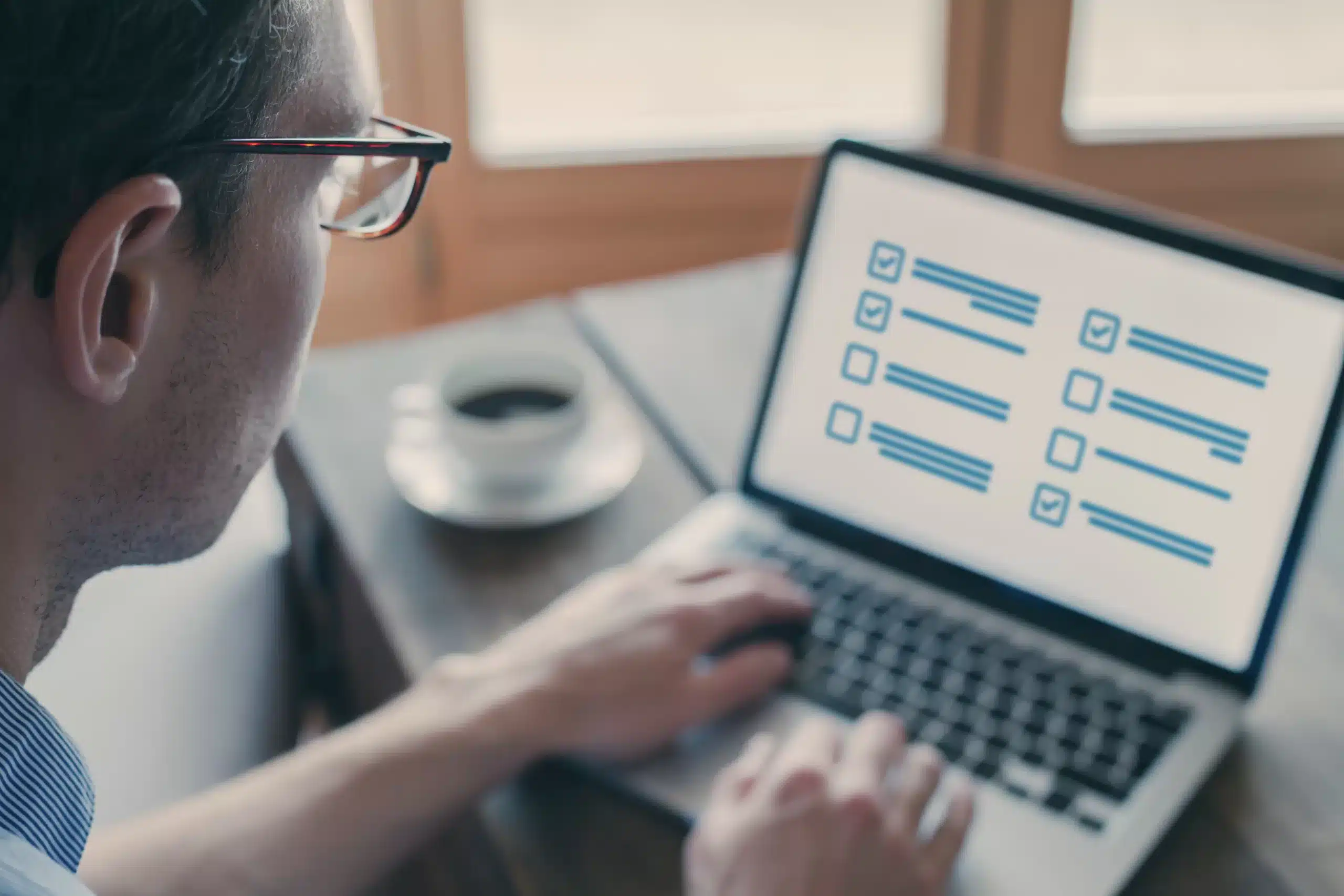 Man using laptop with checklist on screen. Online testing offers scalable, consistent, accessible, speedy, cost-efficient, and data-driven assessments. Wonderlic enhances online testing.