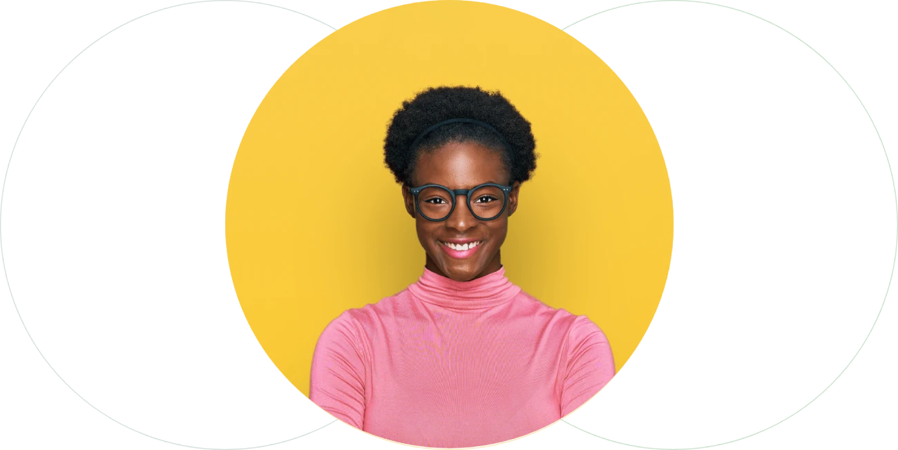 A person with short curly hair, wearing glasses and a pink turtleneck sweater, smiles confidently against a bright yellow background, perfect for a hiring assessment profile.