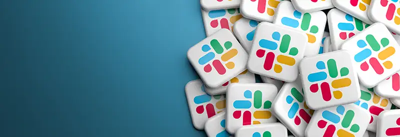 A pile of square buttons displaying the colorful Slack logo, featuring overlapping bars in blue, green, yellow, and red, symbolizes vibrant team dynamics on a gradient blue background with empty space on the left.