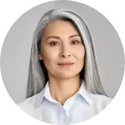 A person with long gray hair and wearing a white shirt is smiling slightly, embodying the calm confidence of someone ready for an employee assessment. The background is a plain, neutral color.